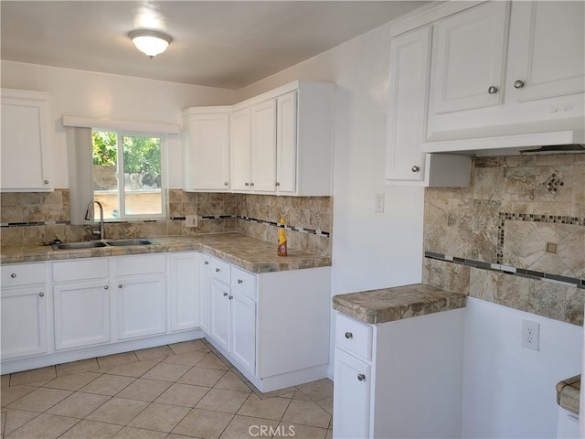 kitchen with backsplash, sink, custom range hood, light tile patterned flooring, and white cabinetry