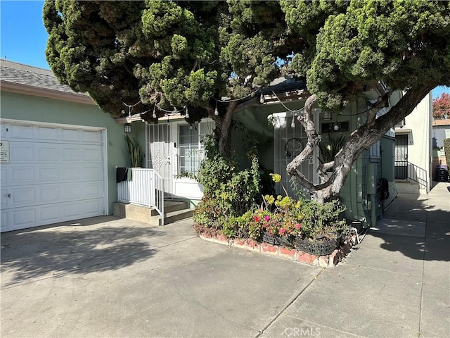 view of front of home featuring a garage, concrete driveway, and stucco siding