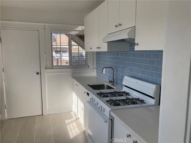 kitchen with under cabinet range hood, a sink, white cabinetry, backsplash, and gas range gas stove