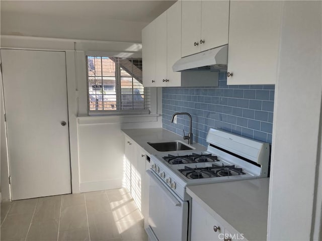 kitchen with baseboards, white cabinets, a sink, under cabinet range hood, and white gas range oven
