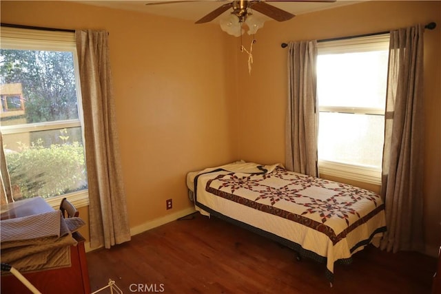 bedroom featuring ceiling fan, dark hardwood / wood-style flooring, and multiple windows