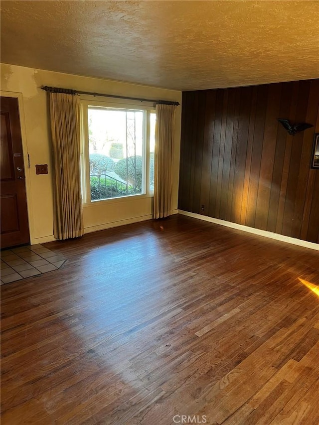 spare room with hardwood / wood-style flooring, a textured ceiling, and wood walls