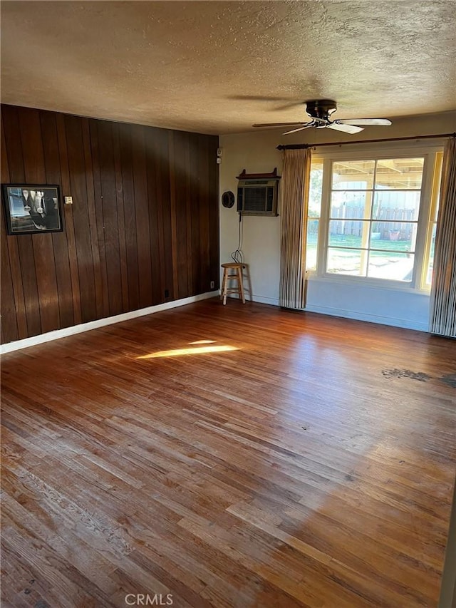 spare room with hardwood / wood-style flooring, a wall mounted AC, a textured ceiling, and wood walls