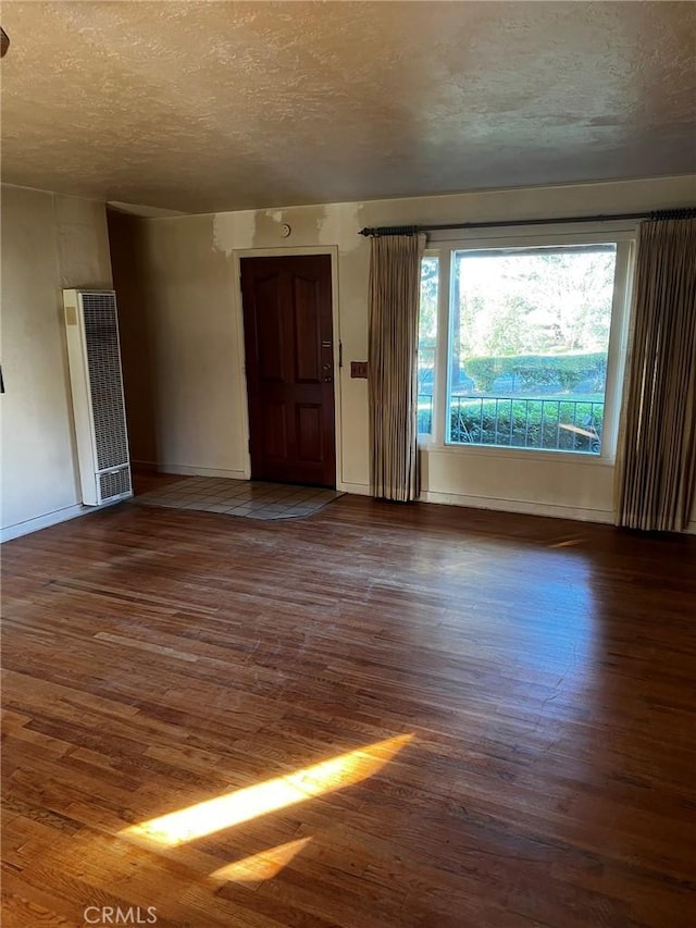 spare room featuring dark hardwood / wood-style floors and a textured ceiling