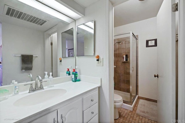 bathroom with tile patterned flooring, vanity, a shower with shower door, and toilet