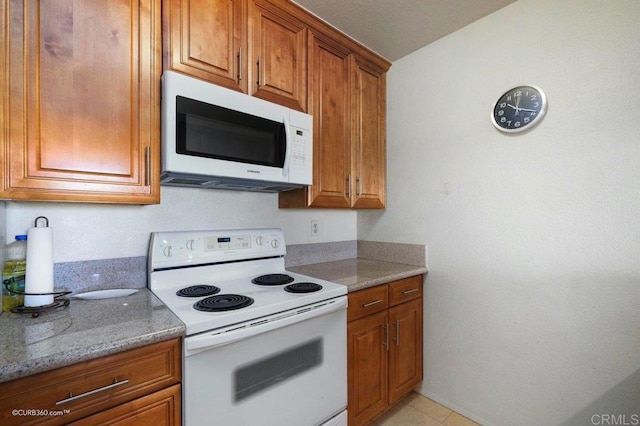 kitchen featuring light stone counters, white appliances, and light tile patterned floors