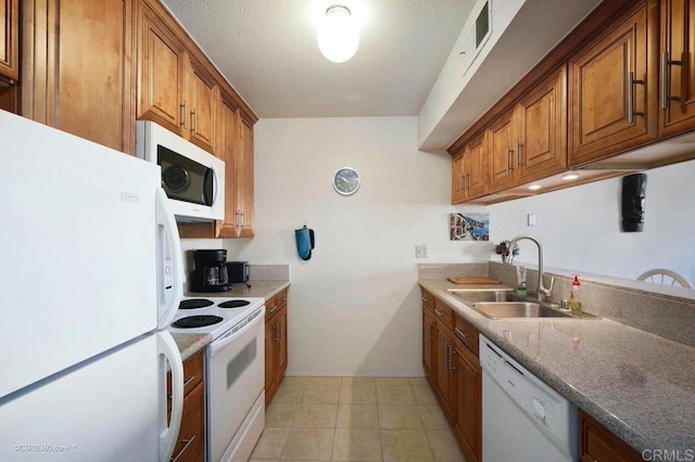 kitchen with a textured ceiling, white appliances, sink, and light tile patterned floors