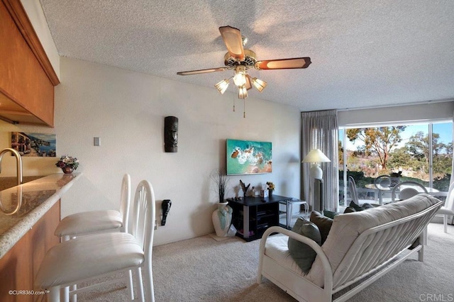 carpeted living room featuring ceiling fan and a textured ceiling