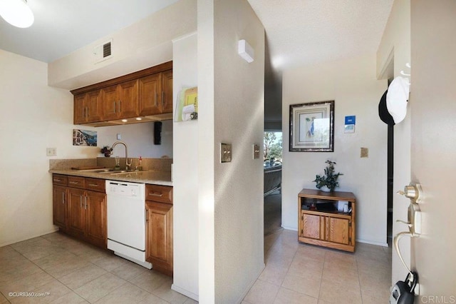 kitchen featuring sink, white dishwasher, and light tile patterned floors