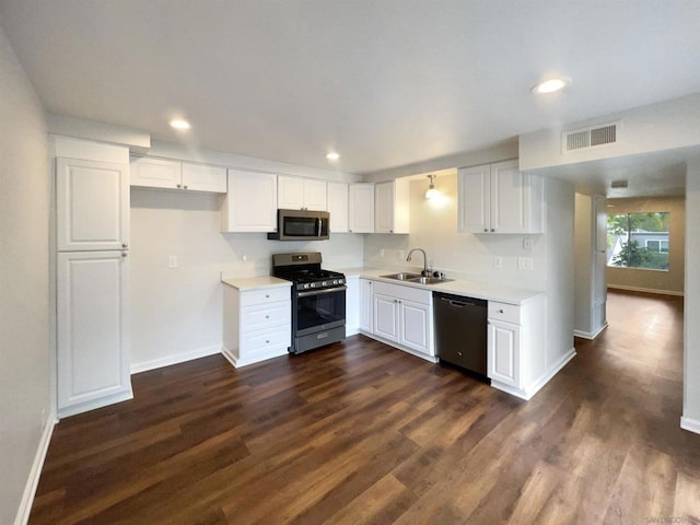 kitchen with appliances with stainless steel finishes, dark hardwood / wood-style flooring, white cabinetry, and sink