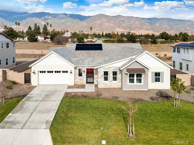 view of front of home featuring a mountain view, a garage, solar panels, and a front yard