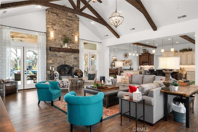 living room featuring beam ceiling, a stone fireplace, dark hardwood / wood-style flooring, high vaulted ceiling, and ceiling fan with notable chandelier