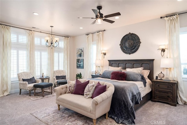 carpeted bedroom featuring ceiling fan with notable chandelier