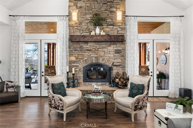 living area featuring dark hardwood / wood-style flooring, a stone fireplace, french doors, and vaulted ceiling