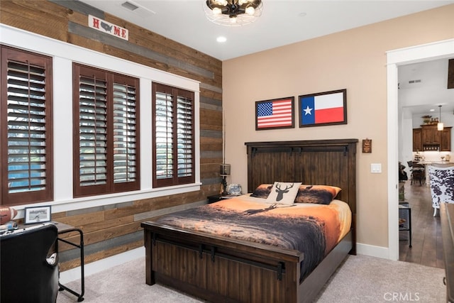 bedroom featuring a chandelier, wooden walls, and light hardwood / wood-style flooring