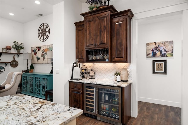 bar featuring dark brown cabinetry, light stone counters, dark hardwood / wood-style flooring, and beverage cooler