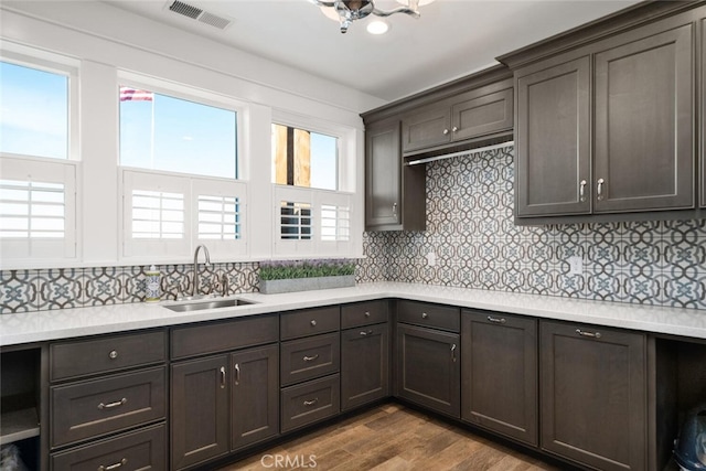 kitchen with decorative backsplash, dark brown cabinetry, dark wood-type flooring, and sink