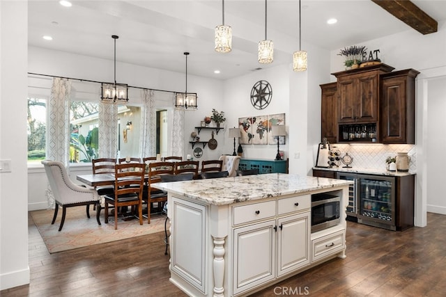 kitchen featuring pendant lighting, dark brown cabinetry, stainless steel microwave, and dark wood-type flooring