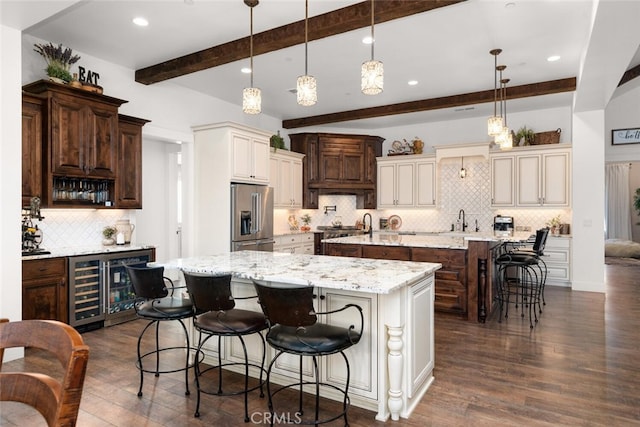 kitchen featuring backsplash, stainless steel appliances, a spacious island, beam ceiling, and decorative light fixtures