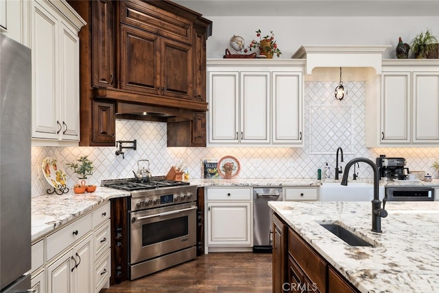 kitchen with appliances with stainless steel finishes, dark hardwood / wood-style flooring, tasteful backsplash, dark brown cabinetry, and sink