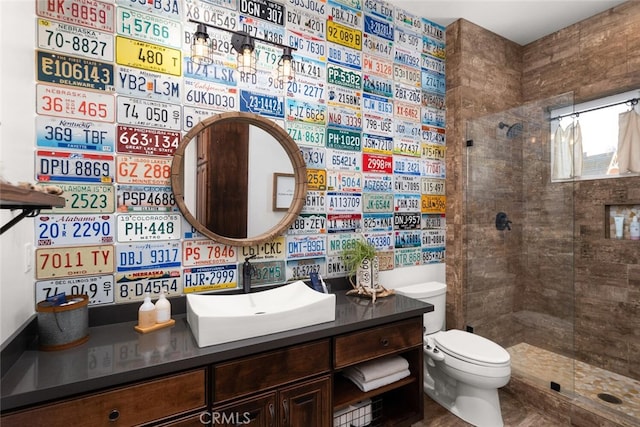 bathroom with tiled shower, vanity, and toilet