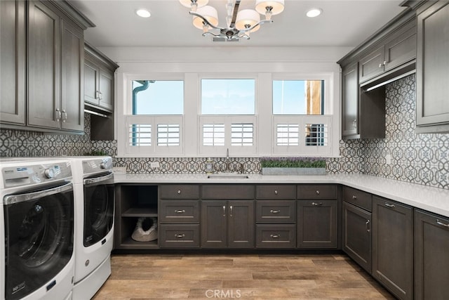 laundry room featuring separate washer and dryer, sink, cabinets, and hardwood / wood-style flooring