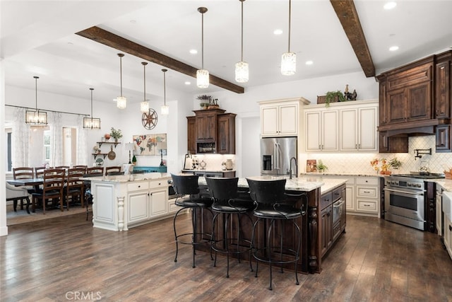 kitchen featuring a center island with sink, beam ceiling, appliances with stainless steel finishes, and pendant lighting