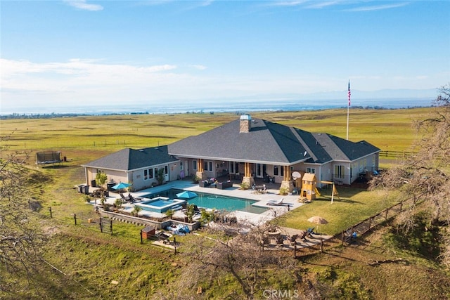 view of pool featuring outdoor lounge area, a yard, a rural view, an in ground hot tub, and a patio