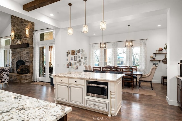 kitchen with dark hardwood / wood-style flooring, stainless steel microwave, a center island, and hanging light fixtures