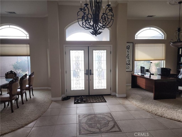 tiled entryway featuring a towering ceiling, ornamental molding, a wealth of natural light, and french doors