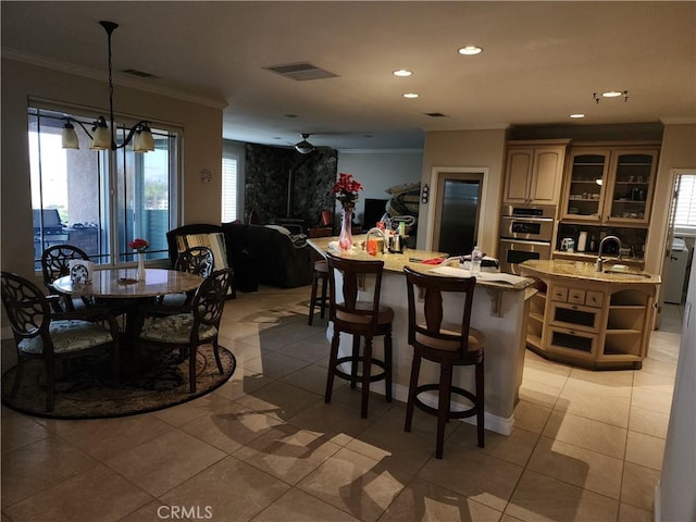 kitchen with a center island with sink, sink, light tile patterned floors, stainless steel double oven, and a chandelier