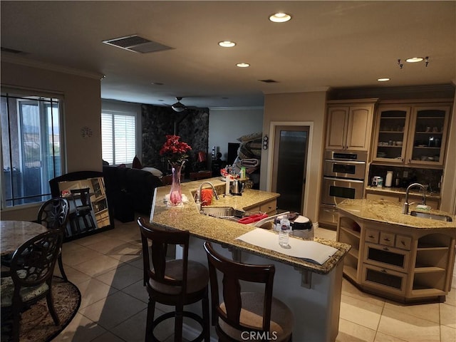 kitchen featuring light tile patterned floors, sink, and a large island with sink