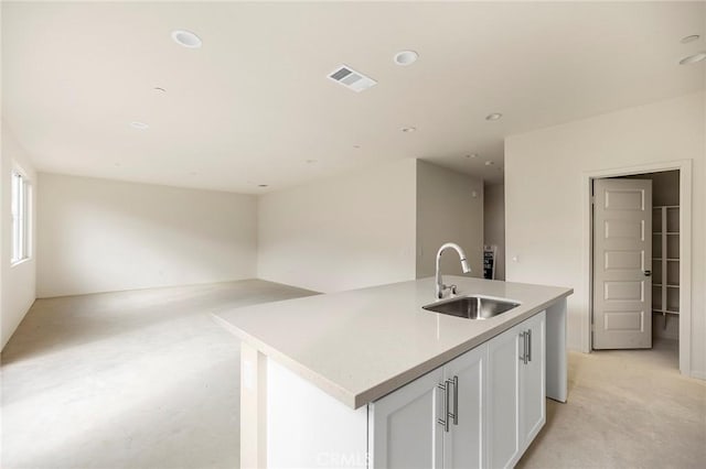 kitchen with white cabinets, sink, and a kitchen island with sink