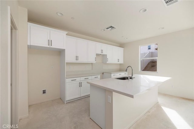 kitchen featuring white cabinets, a center island with sink, and sink