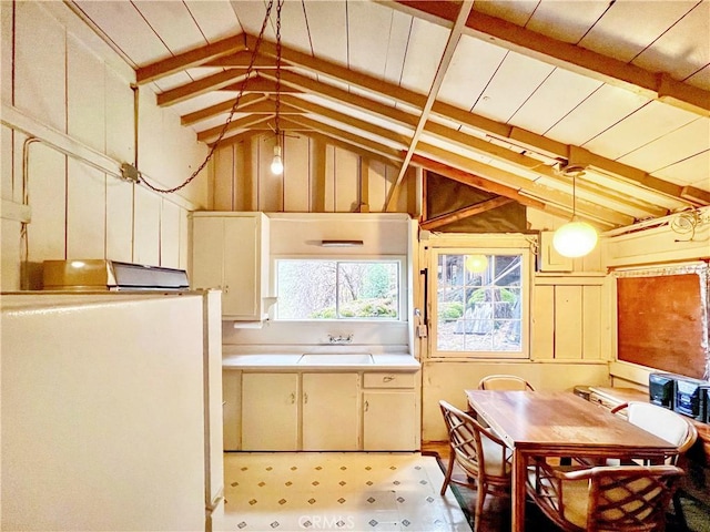 kitchen with cream cabinetry, vaulted ceiling with beams, and white refrigerator