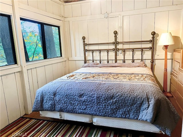 bedroom featuring multiple windows and wooden walls