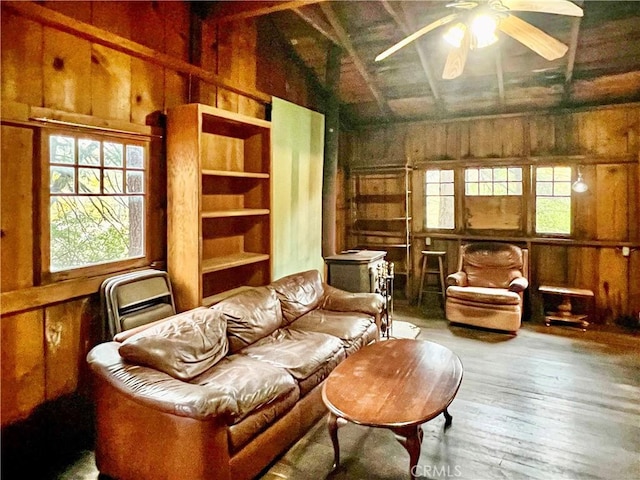 living room featuring hardwood / wood-style flooring, ceiling fan, wooden walls, and vaulted ceiling