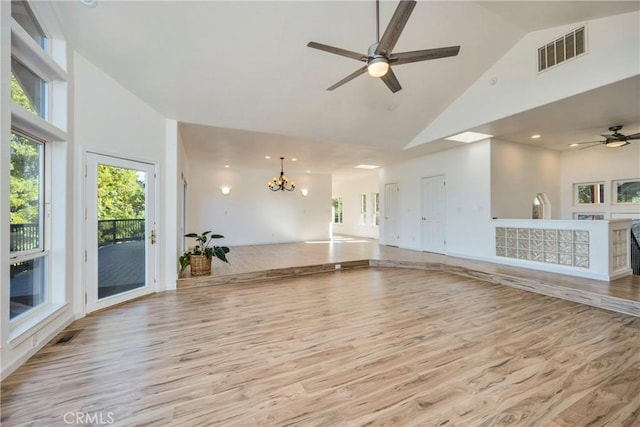 unfurnished living room with ceiling fan with notable chandelier, light hardwood / wood-style flooring, and high vaulted ceiling