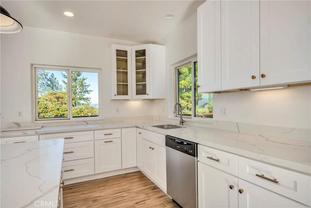 kitchen featuring dishwasher, light stone countertops, sink, and a wealth of natural light