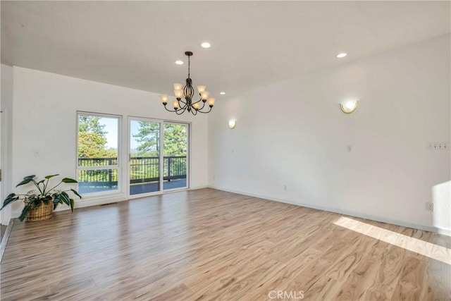 spare room with light wood-type flooring and an inviting chandelier