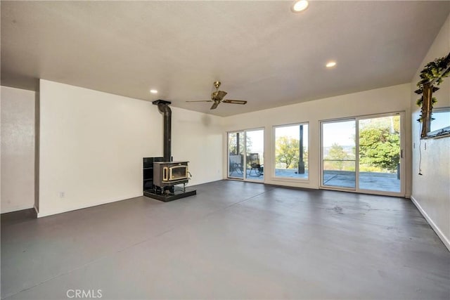 unfurnished living room with a wood stove and ceiling fan