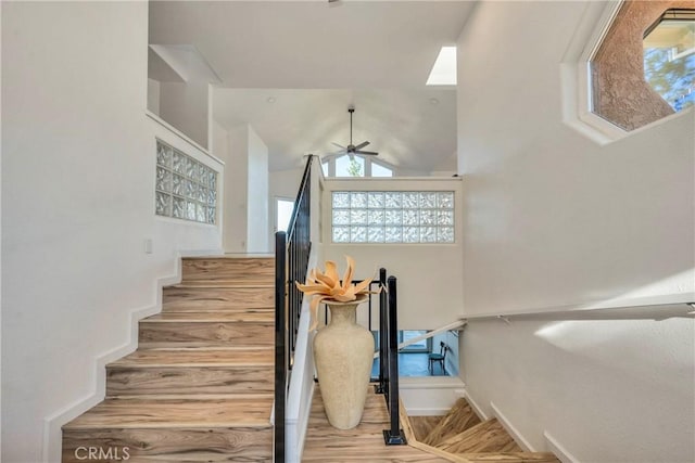 stairway with ceiling fan and lofted ceiling