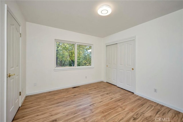 unfurnished bedroom featuring light wood-type flooring and a closet