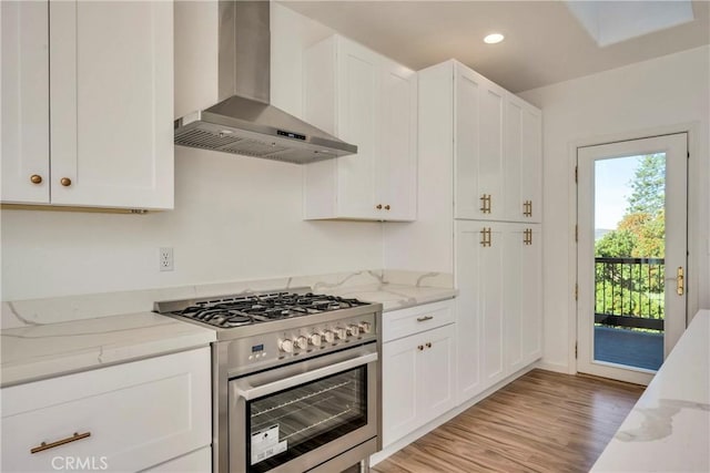 kitchen with white cabinetry, high end stove, and wall chimney range hood