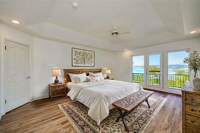 bedroom with access to exterior, dark hardwood / wood-style flooring, a raised ceiling, and ceiling fan