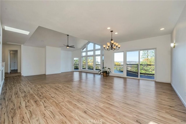 unfurnished living room featuring ceiling fan with notable chandelier, high vaulted ceiling, and light hardwood / wood-style flooring