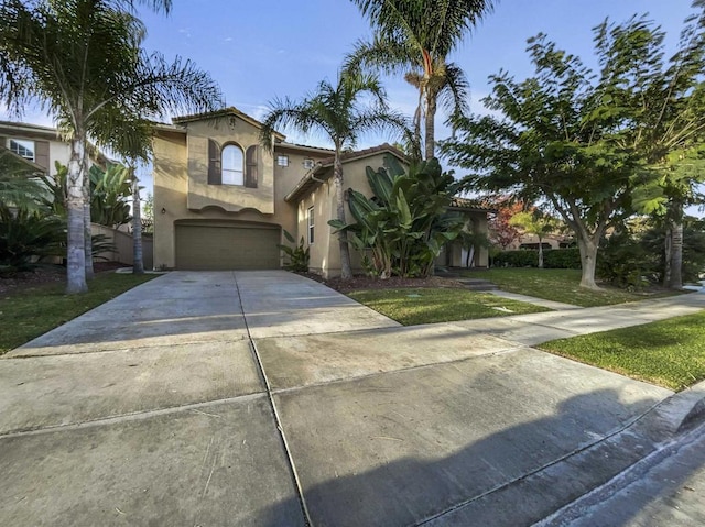 mediterranean / spanish house featuring a garage and a front lawn