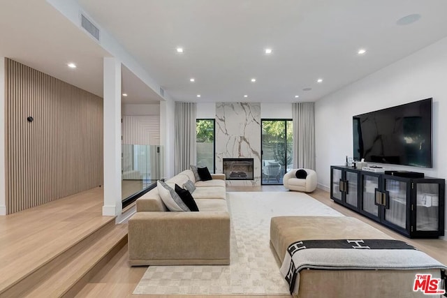 living room with light hardwood / wood-style floors and a high end fireplace