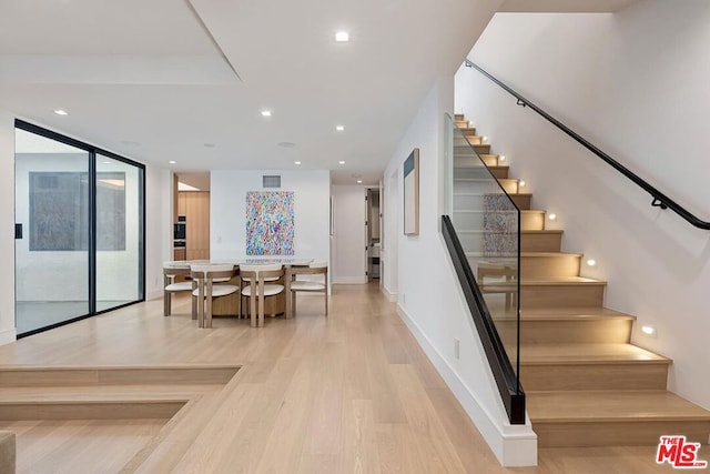 stairs with hardwood / wood-style flooring and a wall of windows