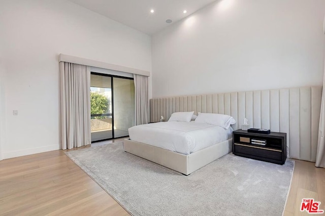 bedroom featuring light hardwood / wood-style floors, a high ceiling, and access to outside